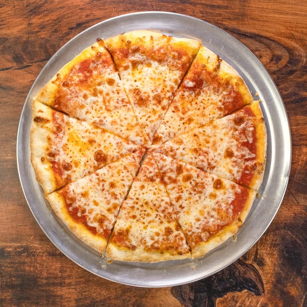 A classic cheese pizza, cut into eight slices, on a metal pan atop a rustic wooden table.