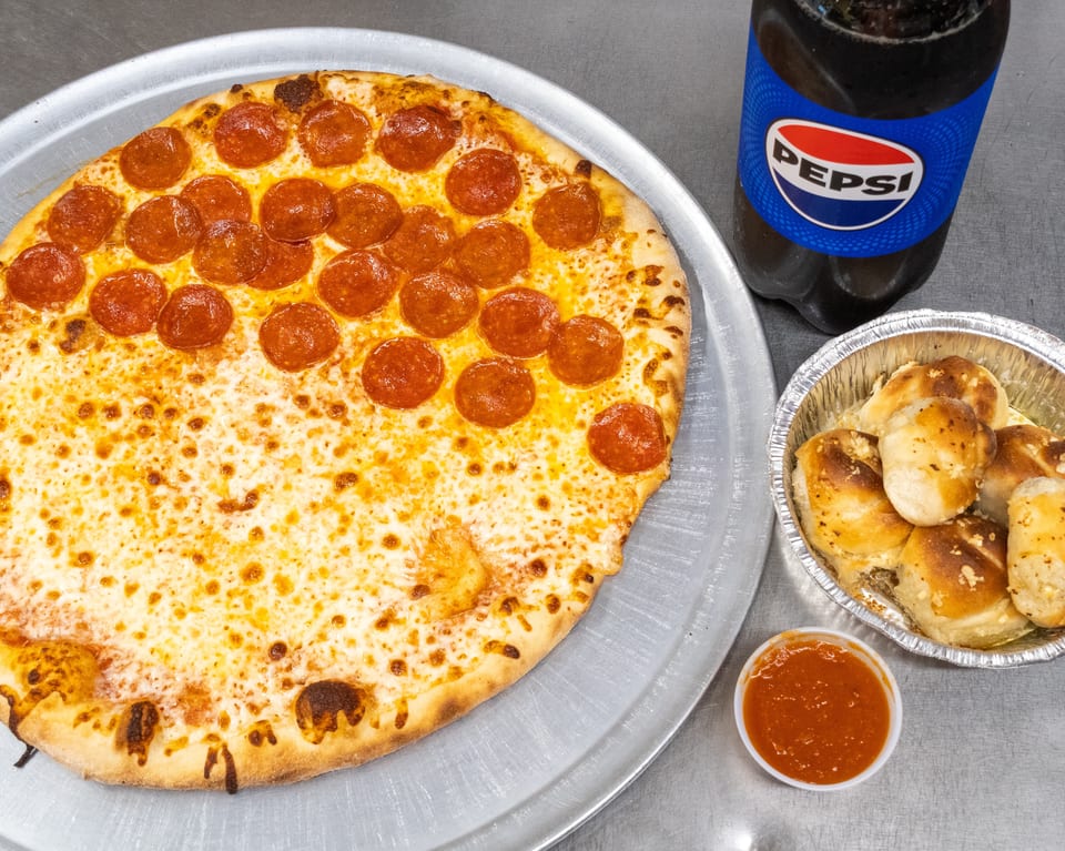 Pepperoni and cheese pizza, garlic knots with marinara, and a Pepsi bottle on a metal surface.
