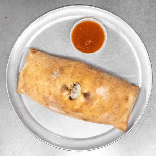 A golden-brown calzone with a small hole revealing cheese, served with a side of marinara sauce.