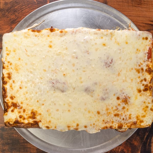A rectangular cheese pizza with a thick crust and bubbly, golden-brown cheese on a metal tray.