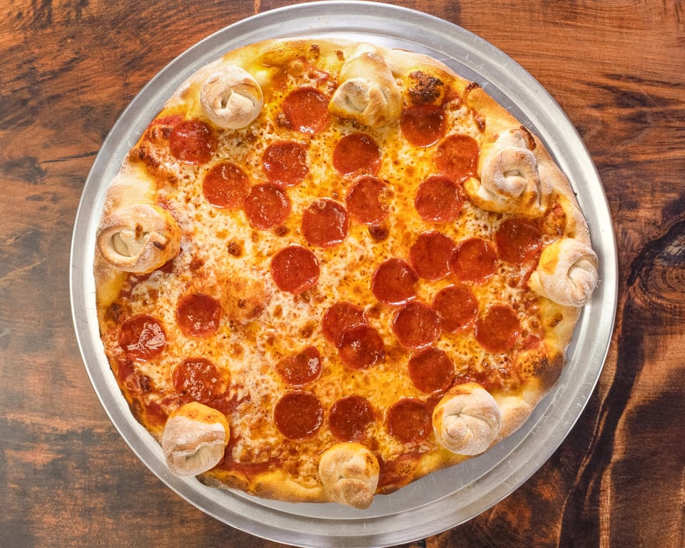 A pepperoni pizza with garlic knots baked into the crust, on a metal tray.