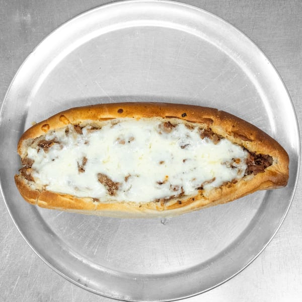 A cheesy steak sub sandwich on a metal tray, viewed from directly above.