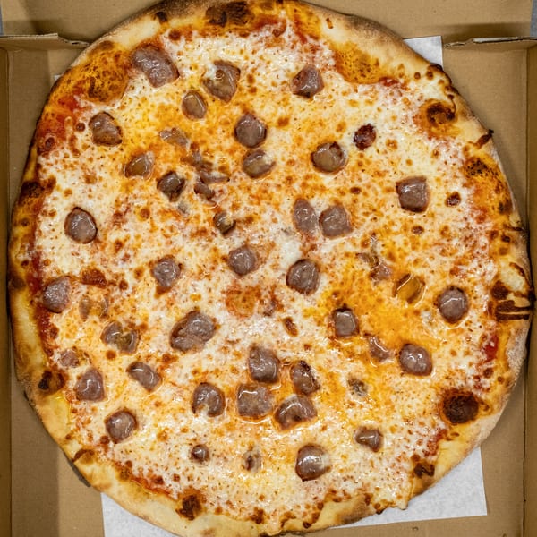 A whole sausage pizza with melted cheese and red sauce in a cardboard delivery box.