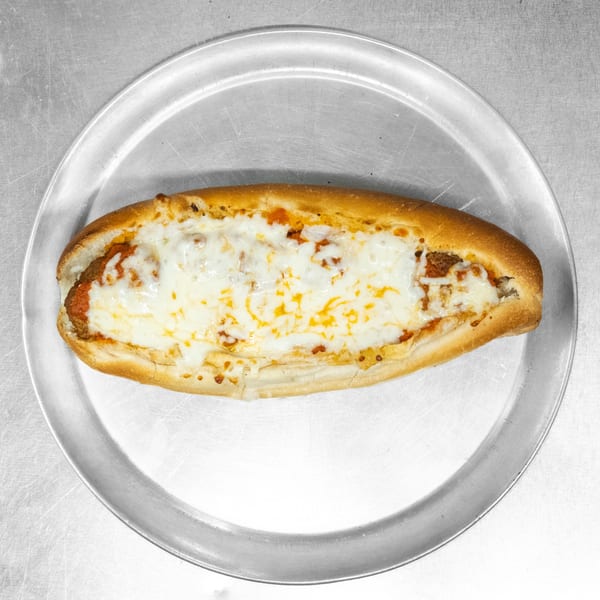 A meatball sub with melted mozzarella cheese and marinara sauce on a metal pizza pan.